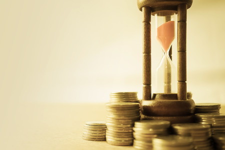 coin money and hourglass for about time of finance concept