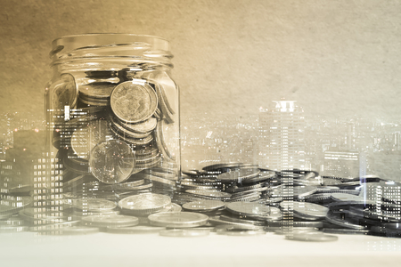 Double exposure of city and coins in the bottle for finance and banking conceptの写真素材
