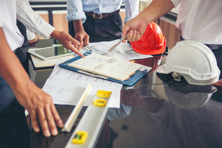 Engineers meeting to work and point to drawings in the office to discuss. Group of businessmen and construction site engineers Workplace engineering objects with partnersの写真素材