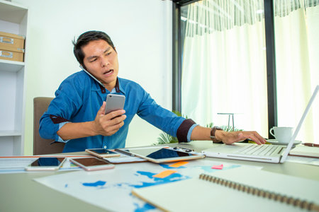 Asian woman wearing headphones using laptop sitting in her bedroom to communicate with friends during the epidemic of COVID-19の写真素材
