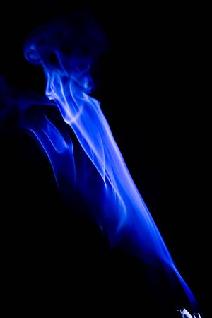 Abstract blue smoke swirls over black backgroundの写真素材