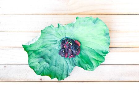 Mulberry on lotus leaves from Thailand on a piece of wood
