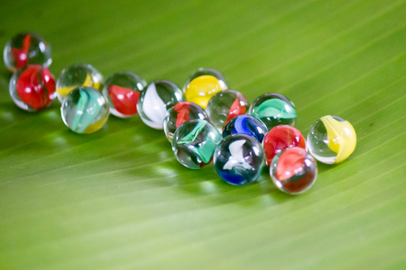 Colorful glass marbles on banana leafの写真素材