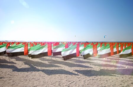 Lot of flags United Arab Emirates for the anniversary celebration on the beach. UAE Natoinal day. Emirates Flag. UAE celebrates National Day on 2nd December every year. Sun ray.の写真素材