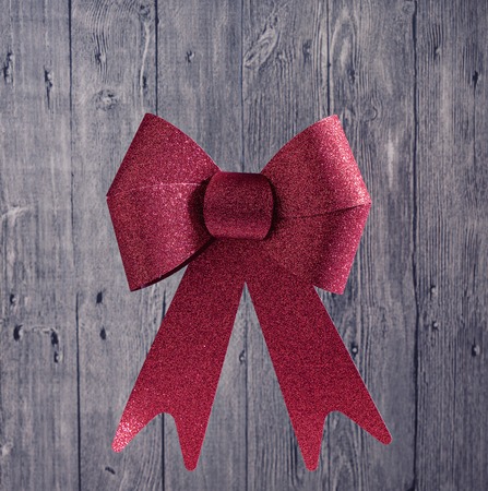 Big Red Christmas Shiny Bow Ribbon on a Wooden Rustic Background, isolatedの写真素材