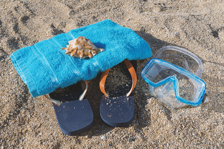 Top view of blue flip flop, snorkel mask and towel on sandy background. Summer leisure activity conceptの写真素材