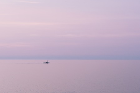 Abstract minimalist scenic view of calm sea with boat and pink sunset, copy spaceの写真素材
