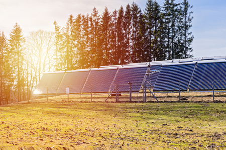 Solar panels on field in rays of sunset. Renewable solar energy concept