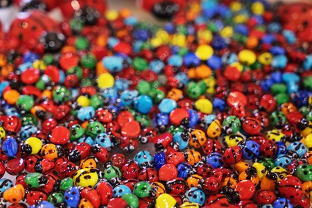 Close up background texture of multicolored glass small ladybugs souvenirs, soft and selective focus