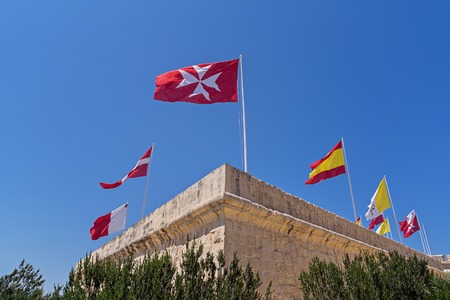 Many different flags over the city of Birgu, Malta against blue clear sky, blowing waving in windの写真素材