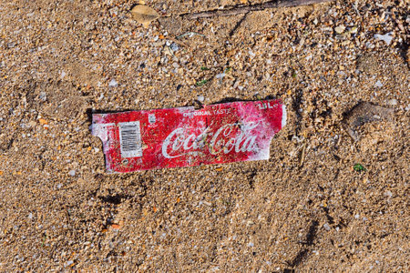Birkirkara, Malta - December 31, 2018: Plastic label from bottle of Coca-Cola on sandy beach after...