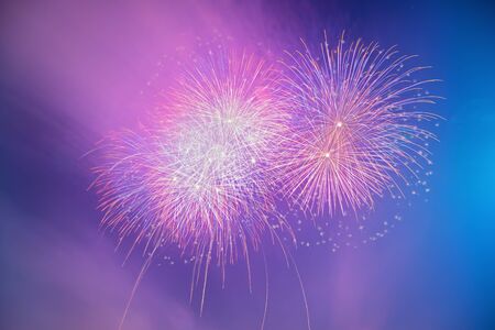 Abstract colorful beautiful fireworks salute against blue sky. Neon Holographic pattern of salute
