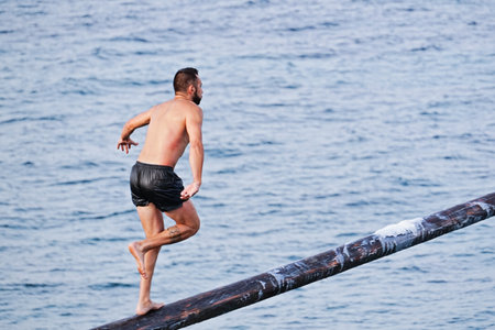 Xghajra, Malta - August 3, 2019: Traditional Maltese game of Gostra, where is Brave local men would try to run up pole and reach one of symbolic flags at top in order to claim prizeのeditorial素材