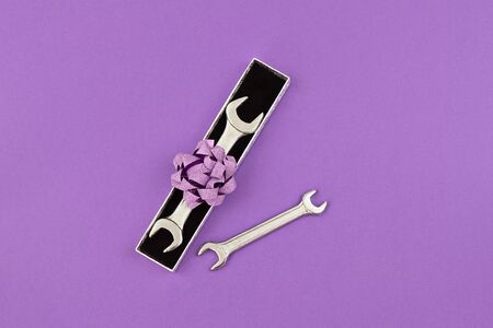Happy Fathers Day flat lay. Wrenches in gift box with bow on purple background. Greeting card to celebrate Father's day with copy spaceの写真素材