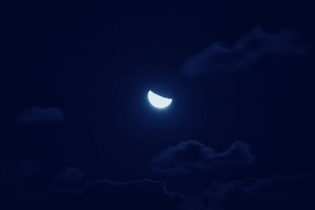Half of bright moon among dark clouds in night sky with motion blur. Moon gathering conceptの写真素材