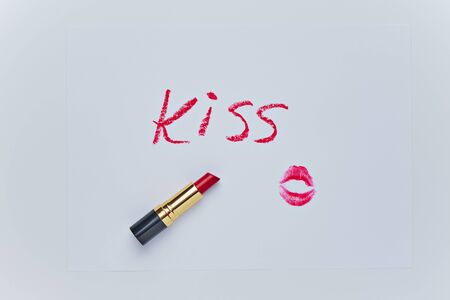 Text KISS drawing and trace of kiss by red lipstick on white sheet. Sketch closeup on white backdrop. Valentines day romantic background. Simple shape.の写真素材