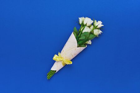 Bouquet of white roses wrapped in tortilla on classic blue background. Concept of edible, zero waste...