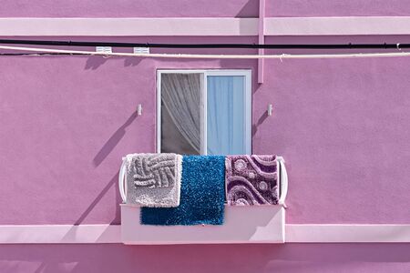 View of authentic balcony. Carpets hang on balcony in the sun. Facade of residential building, copy spaceの写真素材