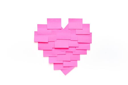 Blank pink sticky notes stick to white wall in heart shape. Valentine day concept in officeの写真素材