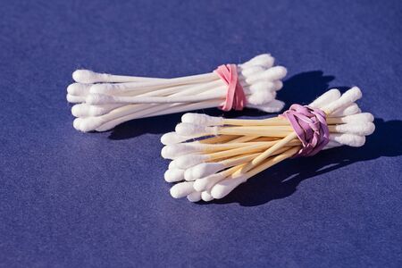 Bamboo cotton sticks versus plastic cotton sticks on purple background. Copy space, zero waste...