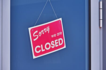 Signboard with inscription SORRY WE ARE CLOSED on glass closed-door, closeup. Job loss concept....