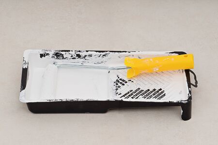 Closeup roller in tray with white pint, nobody