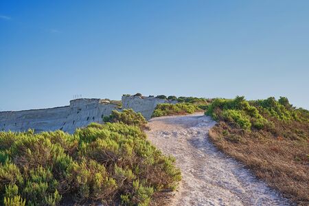 View of dirt road along cliff above sea bay near Marsaskala, Maltaの写真素材