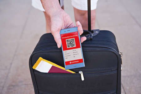 Smartphone in hand displaying on app mobile expired digital vaccination certificate for Covid-19