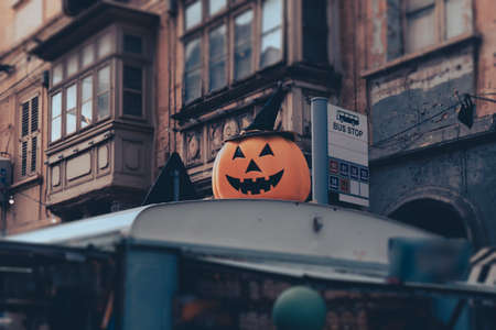 Big smiling pumpkin in hat on roof of street food truck during Halloween holiday as decoration on streetの写真素材