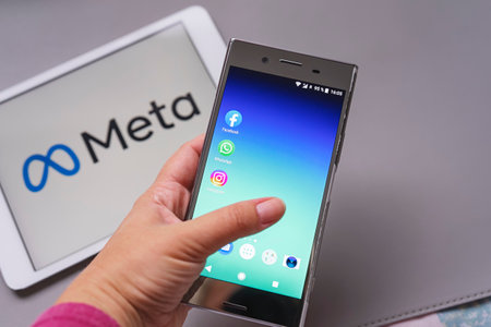 Smartphone display with logo of Facebook, WhatsApp and Instagram apps in hand in against blurred META logotype on white background tablet monitor: Tallinn, Estonia - October 29, 2021のeditorial素材
