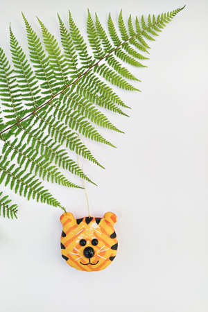 Handmade tiger head bauble hanging on fern leaf. Tiger is symbol of 2022 by Chinese calendar. Zero Waste Christmas conceptの写真素材