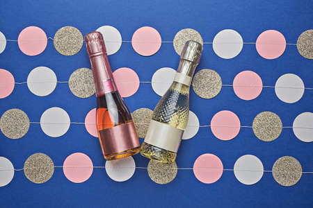 Two festive champagne bottles on blue background with multicolored confetti. New Year celebration conceptの写真素材