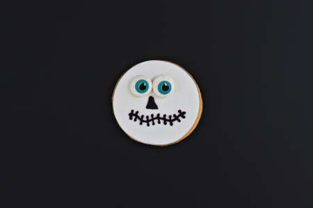 Spooky funny handmade cookie face with big eyeballs on black backgroundの写真素材