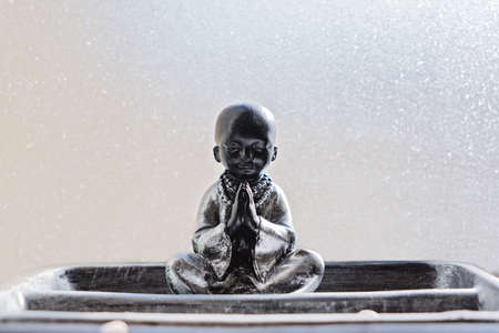 Buddha statue in lotus position against light background. Abstract wellbeing cocnept. Vesak day greeting cardの写真素材