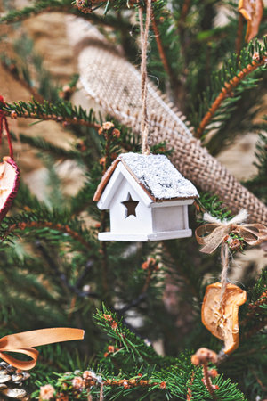 Vintage wooden toy house on Christmas tree. Natural Xmas ornaments for Christmas tree, zero-waste, closeupの写真素材