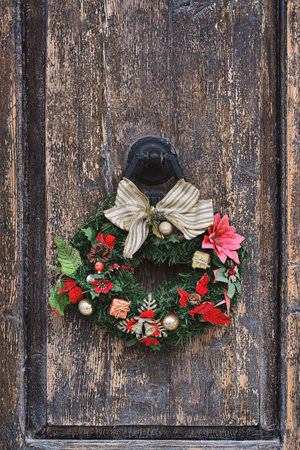 Christmas crown wreath upon an old wooden door. Traditional home decor during Christmas, verticalの写真素材