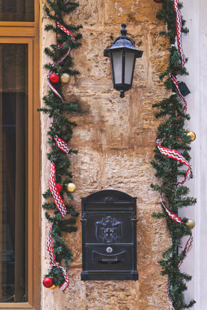 Window and brick front wall of old residential home decorated for Christmas holidays with wreath trees and garlandの写真素材