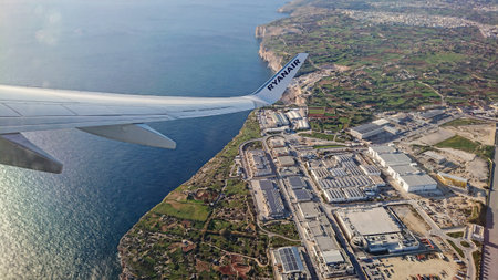 Aerial view from Ryanair airplane wing showing coastal landscape of Malta with blue sea and an industrial zone during flight: Luqa, Malta 9.01.2020のeditorial素材