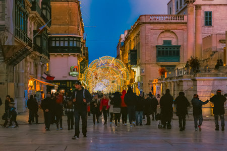 Vibrant street in Valletta, Malta, adorned with glowing Christmas decorations and lights, bustling with pedestrians during twilight hours: Valletta, Malta 30.12.2017のeditorial素材