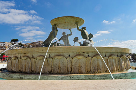 Valletta iconic Triton fountain stands near city gate entrance, fountain representing Maltese heritage. Fountain greets visitors with dynamic water arcs, encouraging vibrant urban atmosphereの写真素材