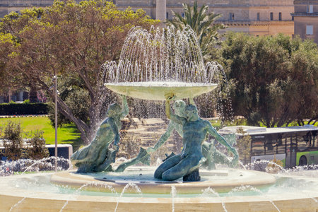 Iconic Triton fountain in Valletta reveals dynamic flow of swirling water, fountain capturing intricate bronze sculpture, fountain symbolizing Maltese heritage, inspiring urban prideの写真素材