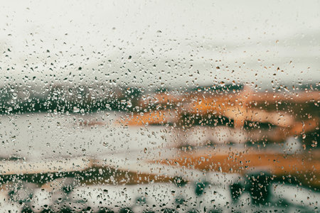 Close up of raindrops on a glass window with a blurred view of a landscape in warm autumnal tones....