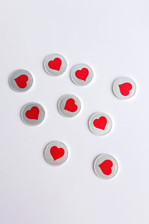 Round white stickers with red heart symbols arranged on clean white paper in simple minimal style