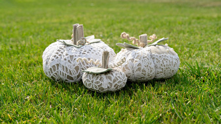 Trio of handmade lace pumpkins resting on bright green grass, rustic neutral tones and soft daylight create cozy garden moodの写真素材