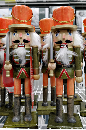 Wooden nutcracker soldiers holding swords, green uniforms and orange hats on store shelf, classic Christmas decor, bright festive moodの写真素材