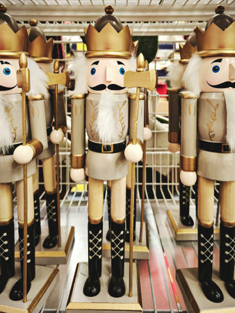 Row of wooden white and gold nutcracker kings with axes and crowns on retail shelf, bright festive moodの写真素材
