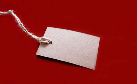 Blank tag tied with string on red background. Price tag label, sale tagの写真素材