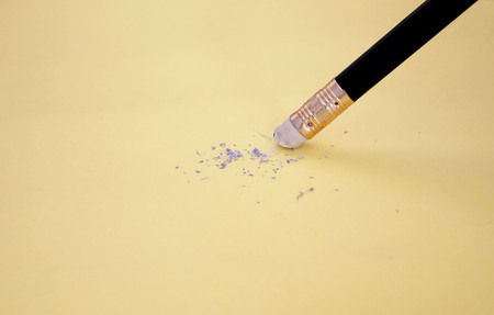 Pencil eraser removing a written mistake on a piece of paper, delete, correct, and mistake concept.