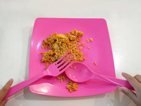 Little child use spoon and fork to eat fried rice.の写真素材