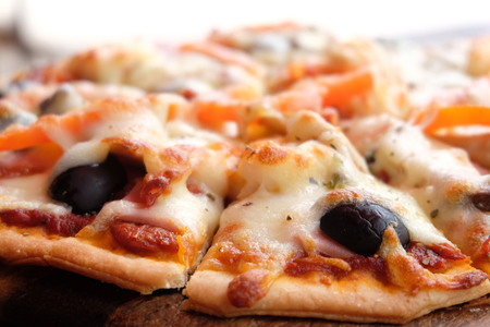 Close up pizza with ham, cheese, tomatoes and olives